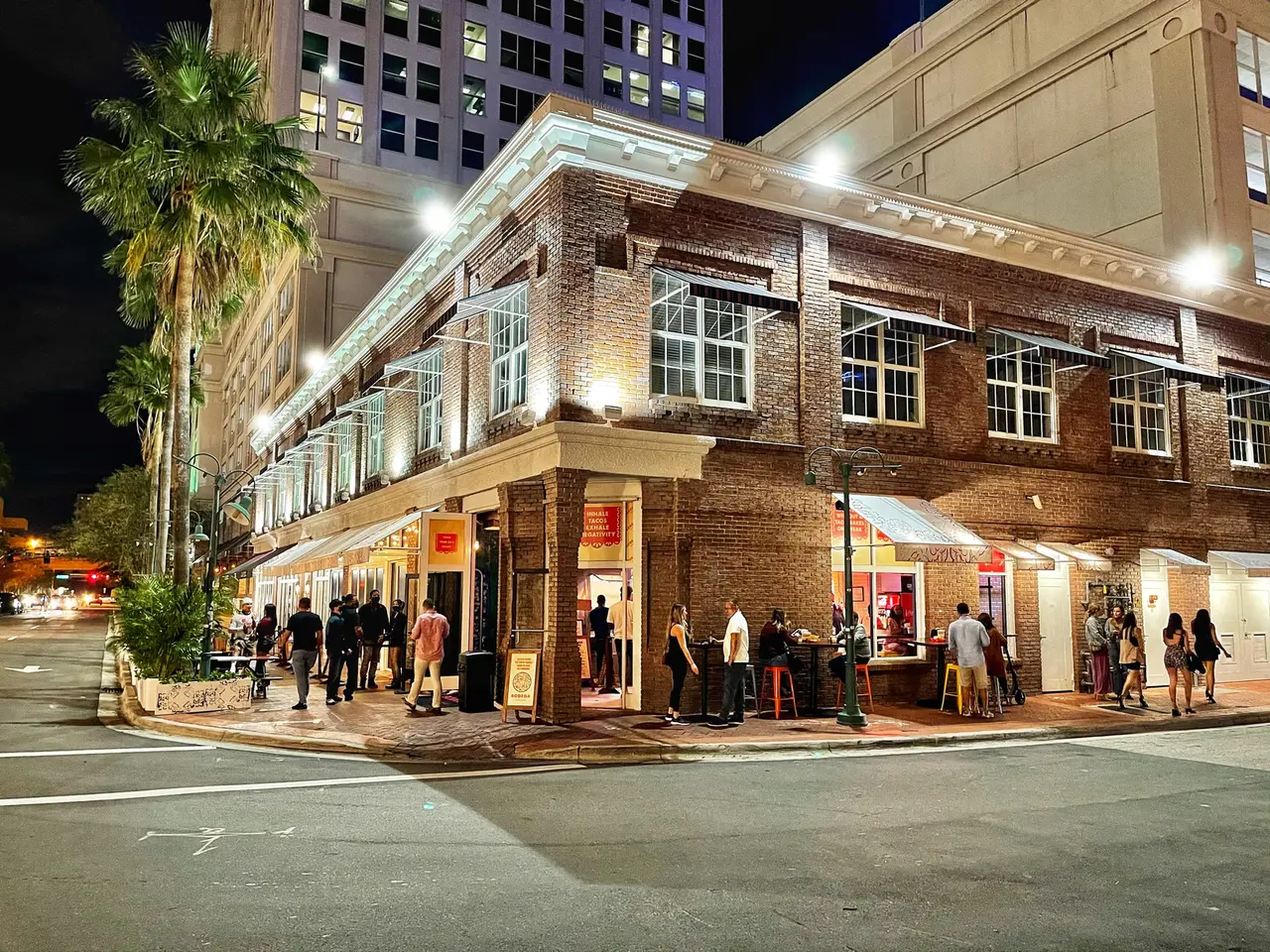 An evening crowd outside a restaurant in a historic brick building in downtown Fort Lauderdale.