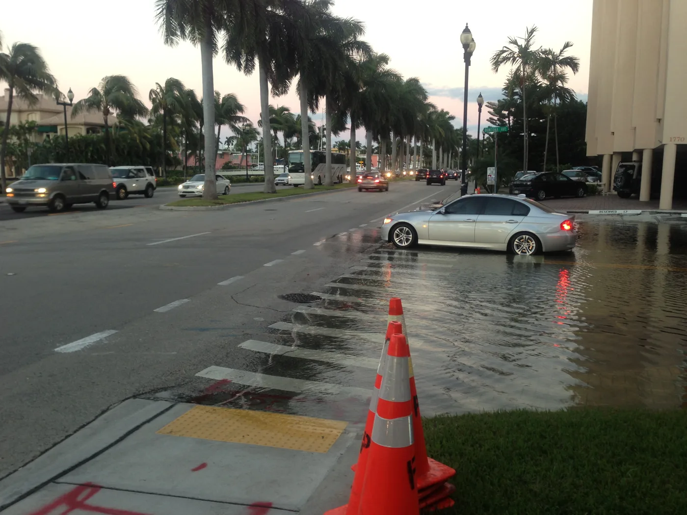 Tidal water across a sidewalk and parking area beside Las Olas Boulevard in Fort Lauderdale at high tide. The picture does not show this week's tides.